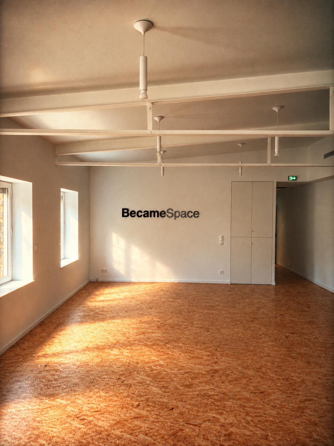 Intérieur du lieu : salle claire au sol d’OSB, poutres apparentes et lettres « BecameSpace » au mur
